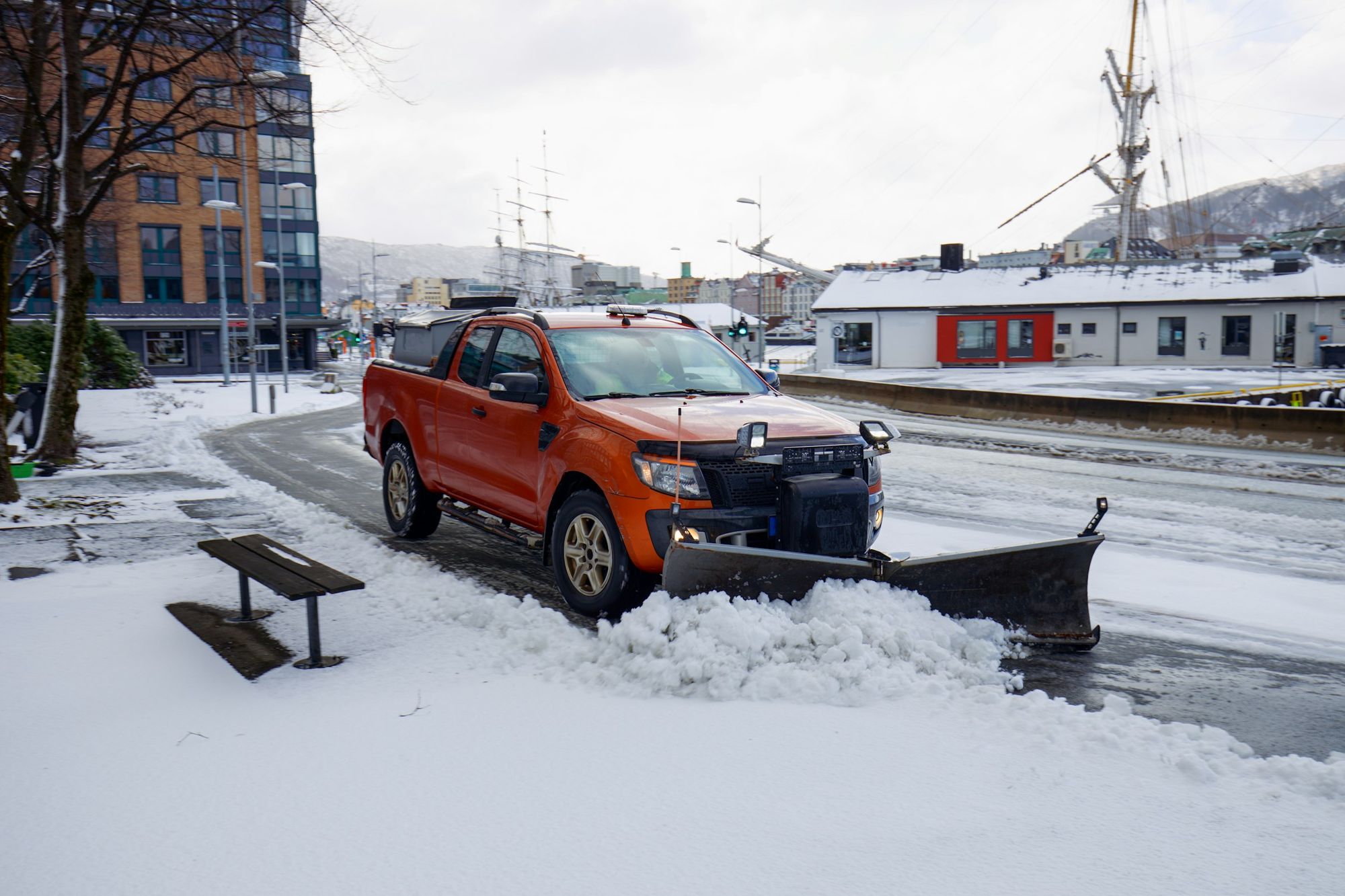 A pickup truck with a snowplow clearing a snowy lot