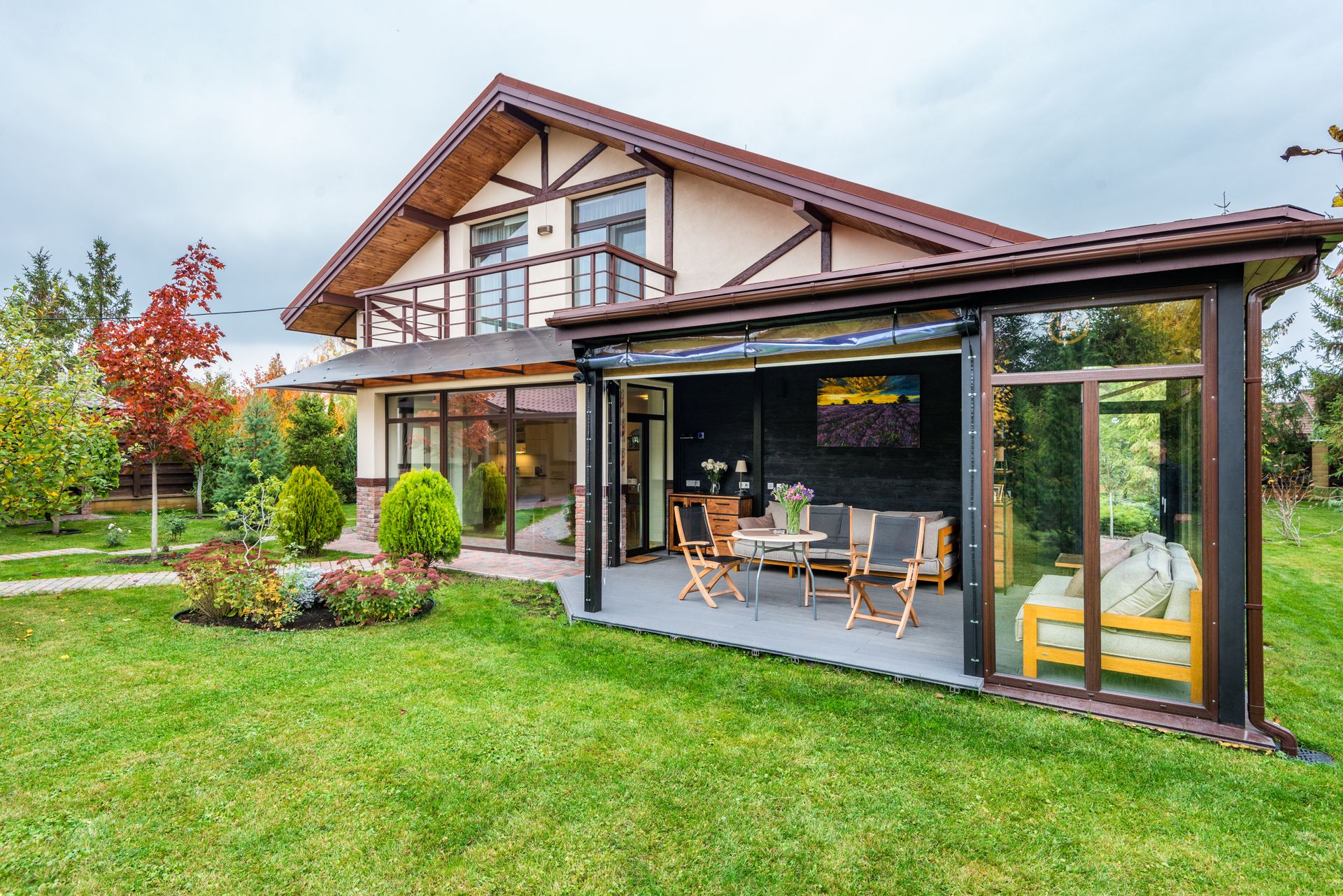 A home with a glass garden room and a well-kept lawn