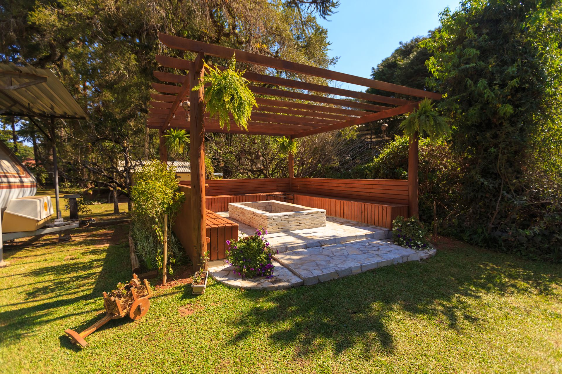 A wooden pergola over an outdoor seating area beside a lawn
