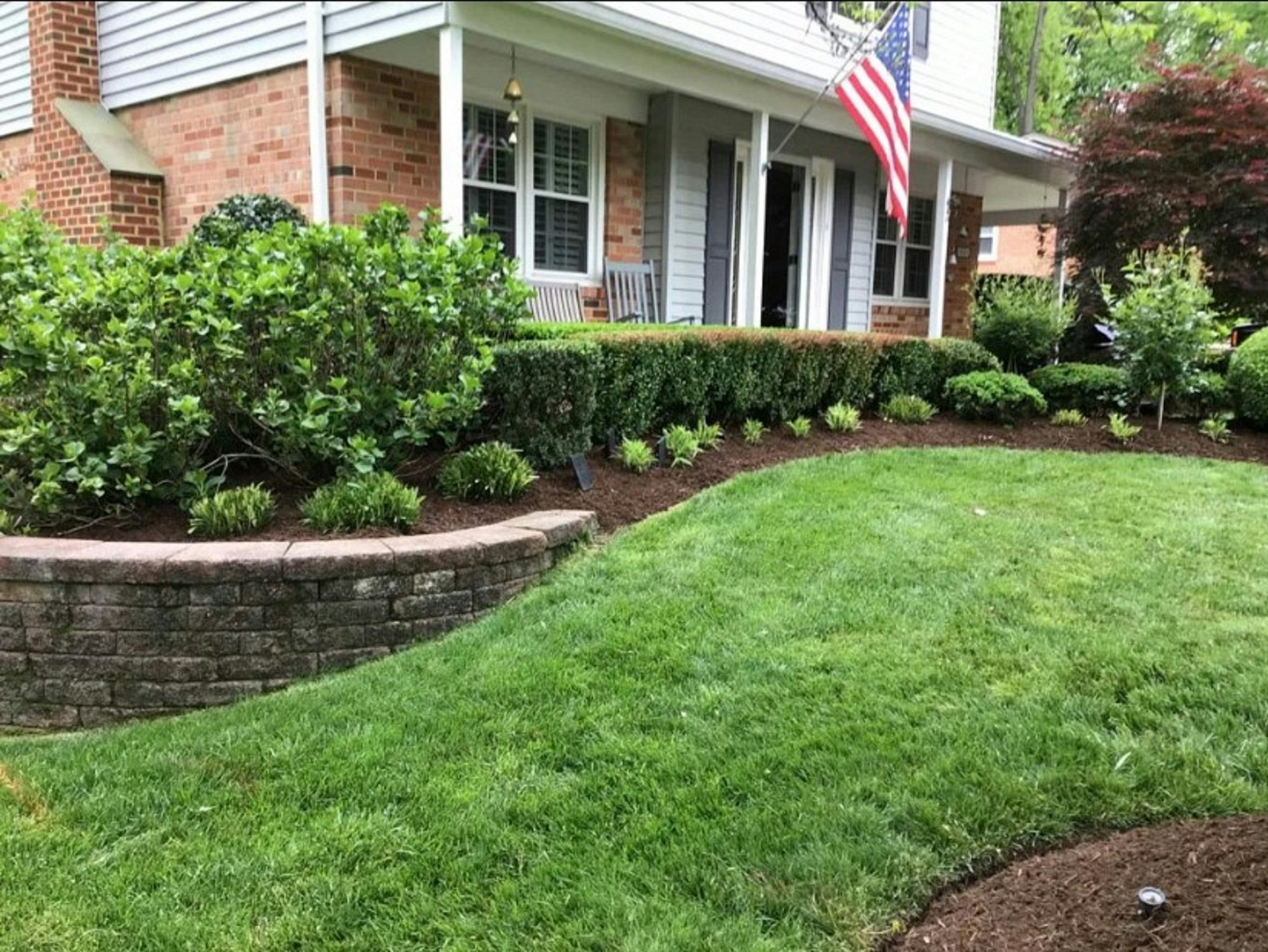 A brick home with a landscaped front yard and planting beds