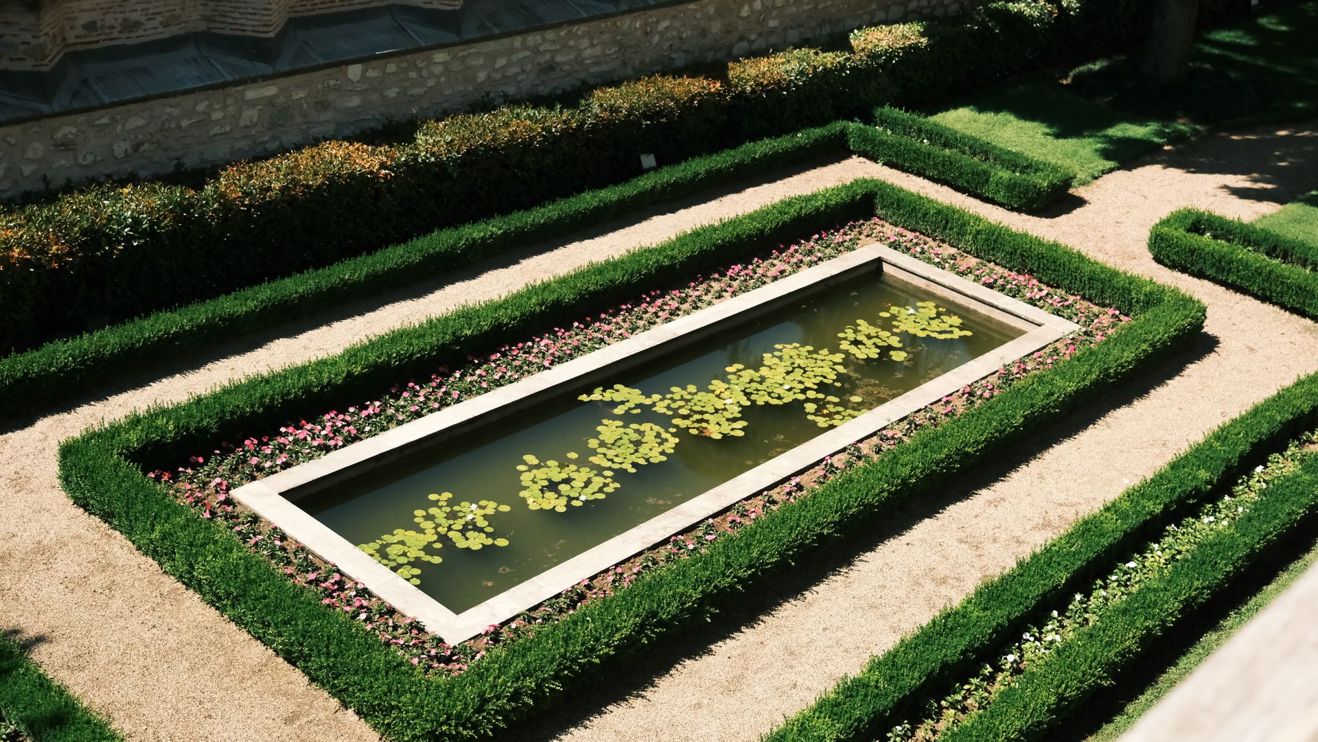 A formal garden with clipped hedges around a long reflecting pool